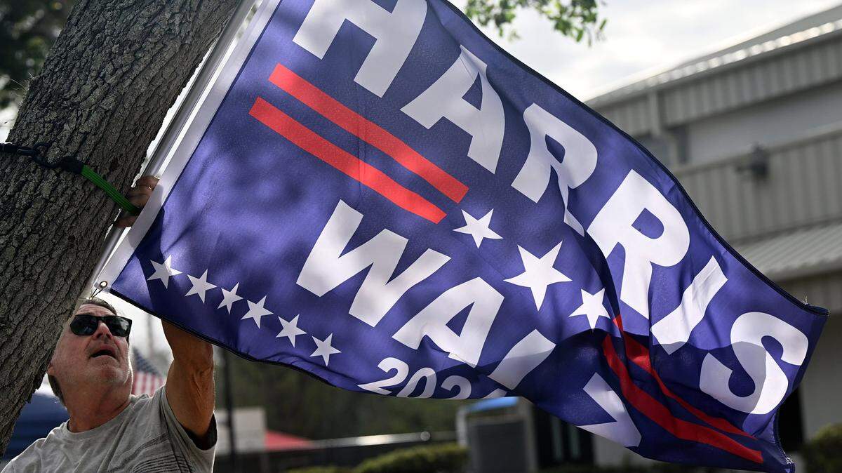 A man hangs a Harris flag outside the building at G.T. Bray in Bradenton on Nov. 5, 2024.