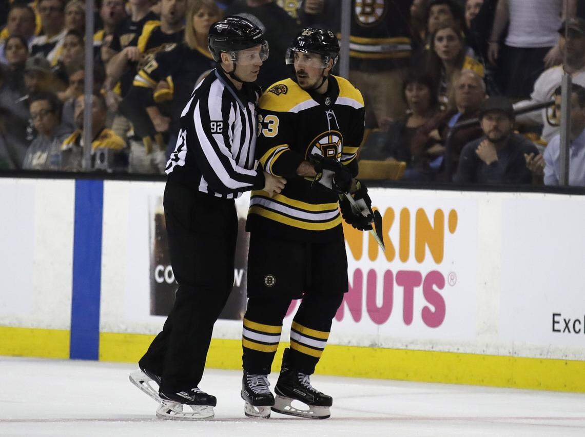 In this May 2, 2018 photo, Boston Bruins left wing Brad Marchand (63) is escorted to the penalty box during the second period of Game 3 of an NHL second-round hockey playoff series against the Tampa Bay Lightning in Boston. The NHL has told  Marchand to stop licking opponents or the Boston Bruins forward will face punishment. Senior vice president of hockey operations Colin Campbell spoke to Marchand and Bruins general manager Don Sweeney on Saturday, May 5 about his actions Friday night against Tampa Bay. Marchand licked Lightning forward Ryan Callahan during Game 4 of their second-round series after appearing to do the same to Toronto’s Leo Komarov earlier in the playoffs.