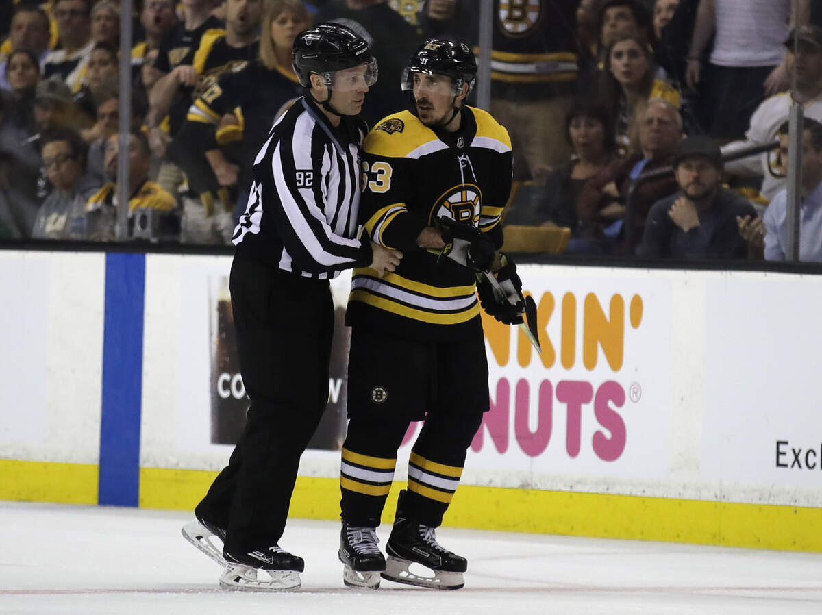 In this May 2, 2018 photo, Boston Bruins left wing Brad Marchand (63) is escorted to the penalty box during the second period of Game 3 of an NHL second-round hockey playoff series against the Tampa Bay Lightning in Boston. The NHL has told  Marchand to stop licking opponents or the Boston Bruins forward will face punishment. Senior vice president of hockey operations Colin Campbell spoke to Marchand and Bruins general manager Don Sweeney on Saturday, May 5 about his actions Friday night against Tampa Bay. Marchand licked Lightning forward Ryan Callahan during Game 4 of their second-round series after appearing to do the same to Toronto’s Leo Komarov earlier in the playoffs.