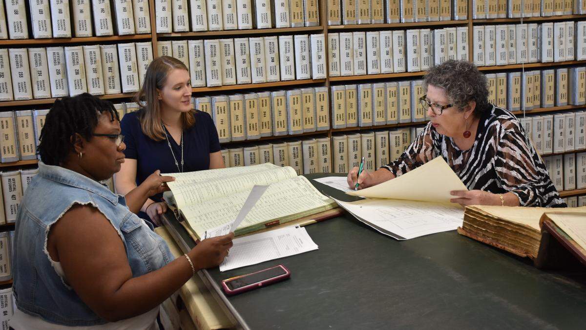 Records Librarian Krystin Miner (middle) helps Tonia Walker-Singleton (left) and Kate Holmes (right) sift through archived records at Saturday's genealogy workshop at the Manatee County Historical Records Library.