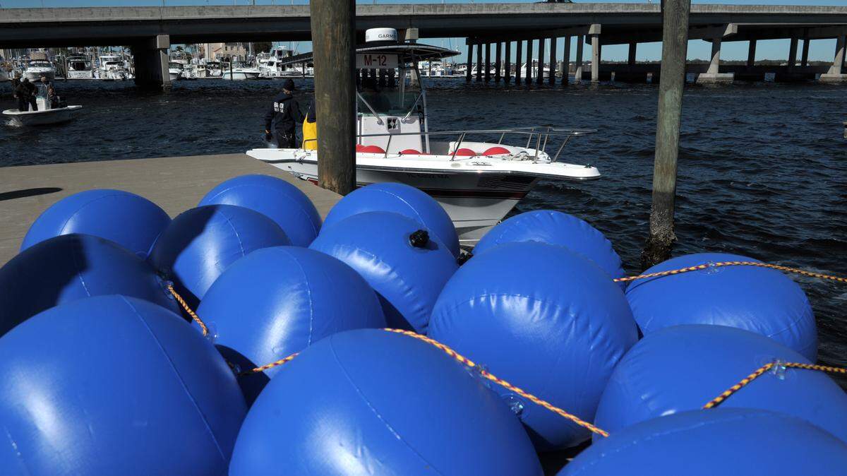 Will Weaver, Jeremy Nance and Matt McCabe, with Bradenton Fire Rescue, prepare to place buoys into the Manatee River on Friday, setting up idle zones, using the blue buoys pictured, and security zones, red, for the Bradenton Area River Regatta on Saturday. 
 GRANT JEFFERIES/Bradenton Herald
