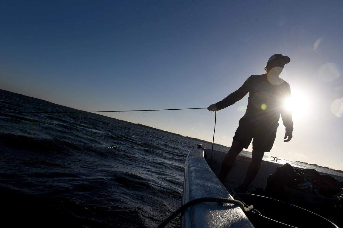 12/15/21—D.J. Strott pulls on the rope anchoring his Carolina skiff in the waters of Tampa Bay. Strott is a clam farmer who supplies wholesalers in the area.