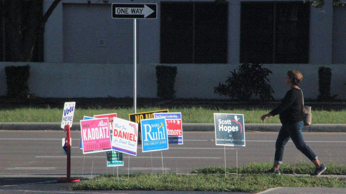 On primary election day a woman walks past election signs posted outside of Oneco United Methodist Church, which serves as Precinct 417 at 2112 53rd Ave. E.