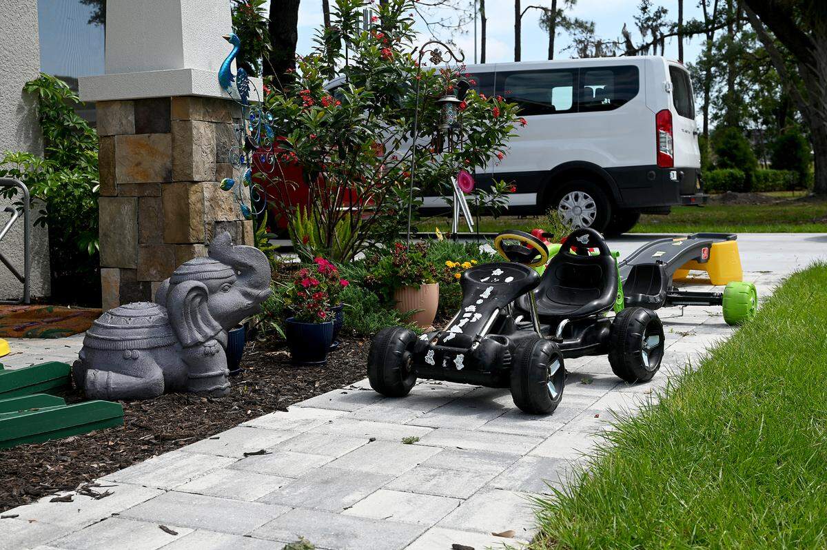 The outside of Mindy and Roy’s home has plants, flowers, and a lot of toys.