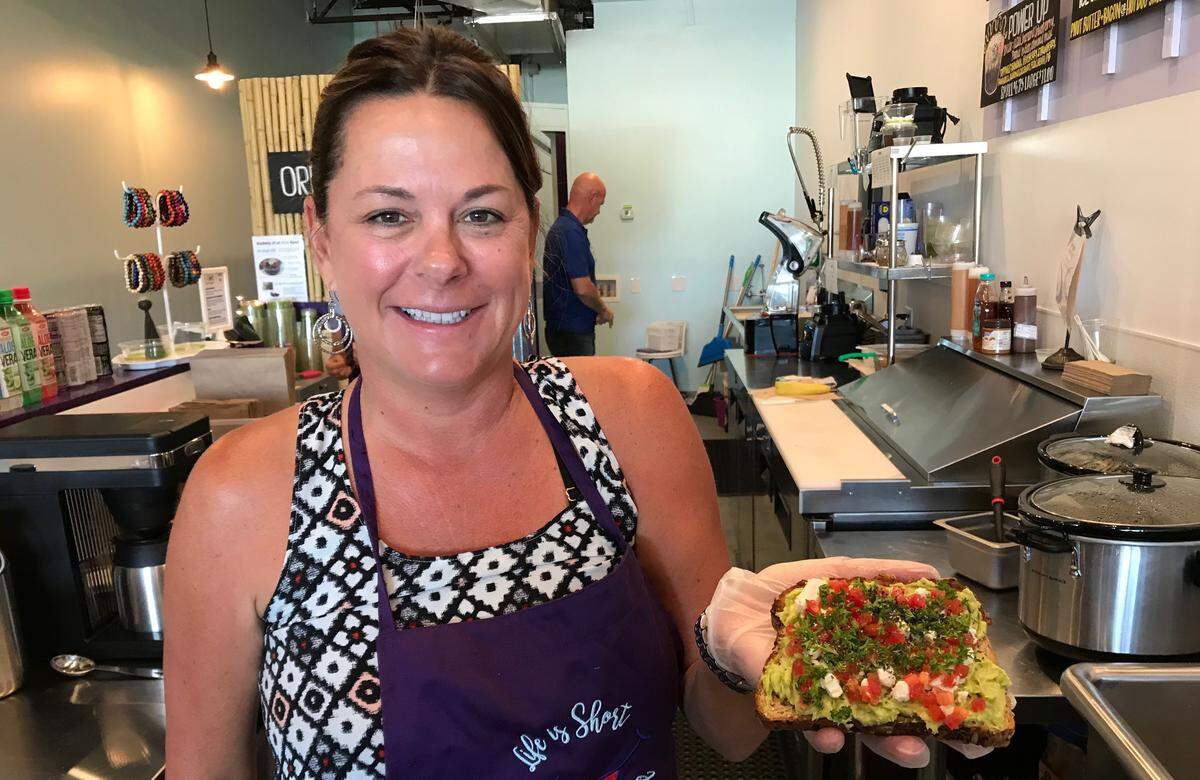 Stephanie Edwards serves avocado toast topped with feta cheese, diced tomatoes, parsley and black pepper at Bowled Life! Cafe in Palmetto.