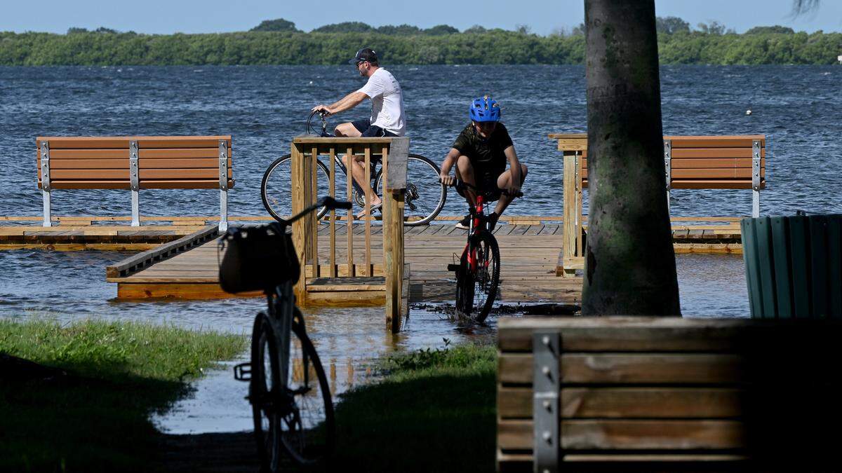 Cyclists have fun on the flooded walkways at Rose Park on Palma Sola Bay as Hurricane Helene approaches Manatee County on Thursday, Sept. 26, 2024.