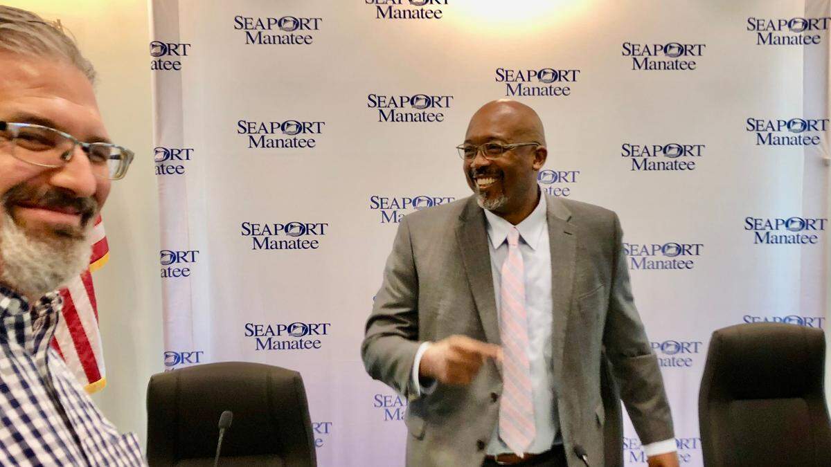 Reggie Bellamy, Manatee County Port Authority chairman, stands in front of a backdrop of SeaPort Manatee logos on 2/17/2022 when the new logo and name were officially announced. At left is Matt Ennis, executive director and chaplain of the Anchor House.