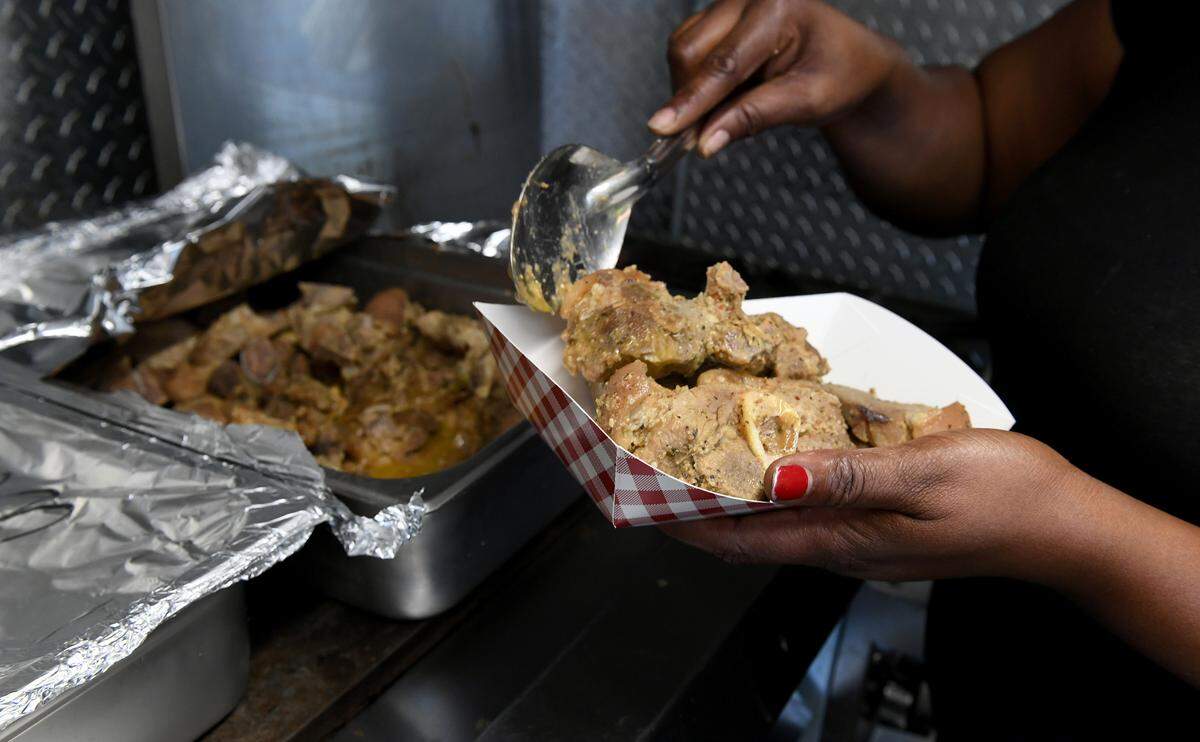 Naomie Germeille, the manager of Sabor Tropical Grill in Bradenton dishes up some of the food their food truck will be serving at the Haitian Flag Day celebration in Palmetto Saturday. Baked chicken, black rice, griot with fried plantains are some of the dishes that will be available. Shown is the pork used in griot.