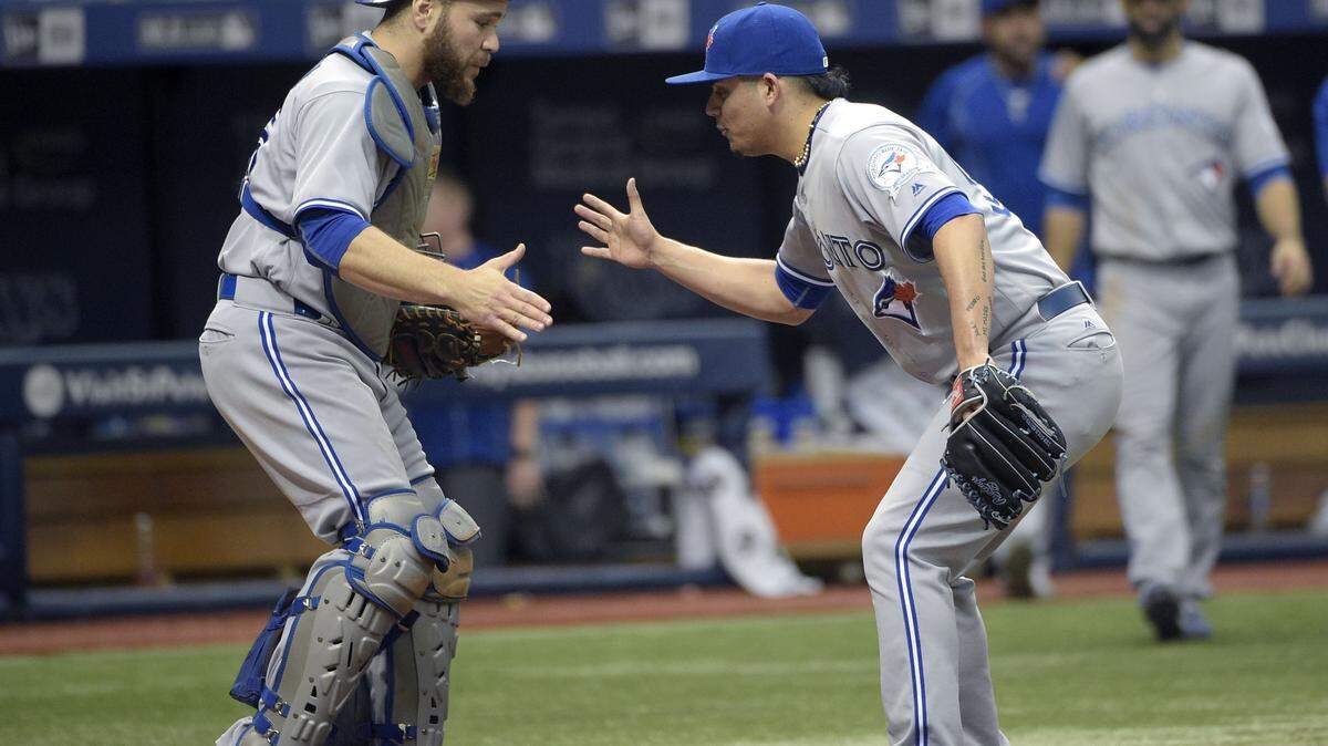 Toronto Blue Jays catcher Russell Martin, left, and relief pitcher Roberto Osuna celebrate at home plate after getting a win over the Tampa Bay Rays during a baseball game in St. Petersburg, Fla., Sunday, May 1, 2016. (AP Photo/Phelan M. Ebenhack)