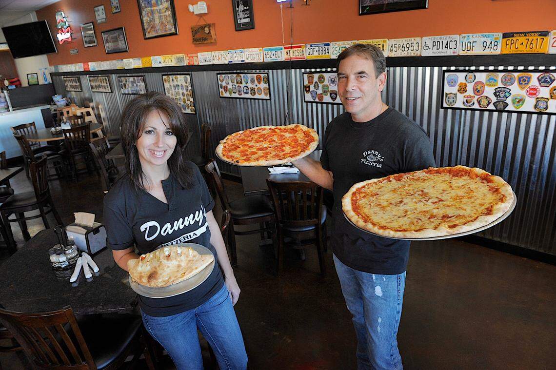 In this Bradenton Herald file photo from 2014, Danny’s Pizzeria owners Danny and Joan Fernandez hold a calzone, one of their most popular entrees, and a pair of hot New York style pizzas fresh from the oven.