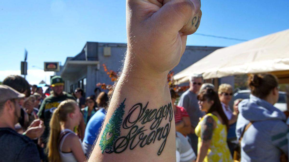 In this Sunday, Oct. 11, 2015, photo, Danielle Hall of Roseburg, Ore., displays her recently minted tattoo in memory of the Umpqua Community College shooting as she joins hundreds of others at Tapestry Tattoo in Roseburg, Ore. Monday was the first day back to campus at Umpqua Community College for students since the deadliest shooting in state history on Oct. 1. (Chris Pietsch/The Register-Guard via AP) MANDATORY CREDIT