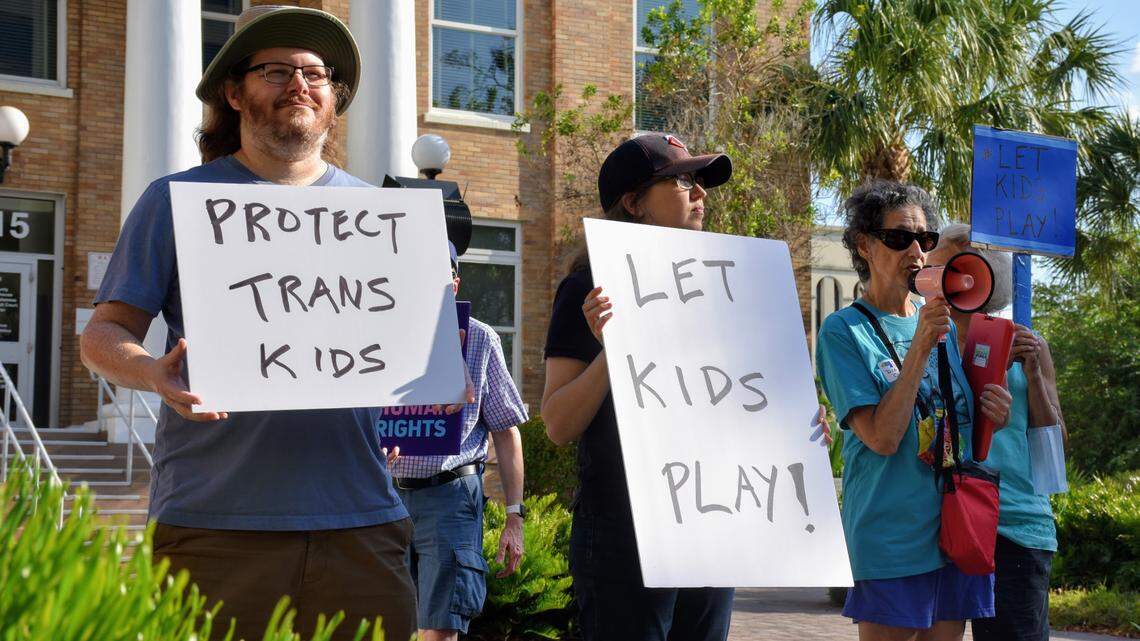 06/01/2021--A handful of protestors took to the streets of downtown Bradenton Tuesday evening to condemn Gov. Ron DeSantis’ latest bill signing, calling it a methodical attack on transgender rights. Republicans say the bill levels the playing field in women’s sports. Diana Cowawns (right) speaks into a megaphone during the demonstration, while Liv Coleman (center) and Matt Lepinski (left) hold signs outside the Manatee County Courthouse.