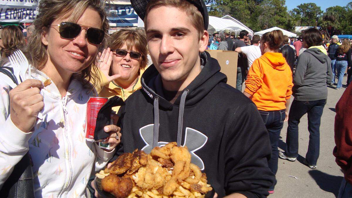 Kobi Hunter of Bradenton holds a Walt's Platter from Walt's Seafood at the annual Cortez Commercial Fishing Festival Sunday. The plate cost $20 and includes flounder, shrimp, conch fritters, soft shell crab, alligator, crawfish, calamari, frog legs, old bay shrimp, blackened mahi, hush puppies and french fries. 
 RICHARD DYMOND/Bradenton Herald