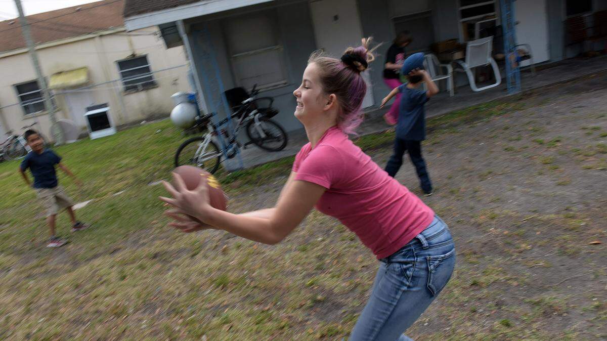 Parkside apartments resident Tabitha Collett, 12, runs after a ball as she plays with other children. The residents of the complex, which has been plagued by crime and challenged by poverty, are trying to clean up the area and build a sense of community by holding pot luck dinners and taking care of each others' needs. 
 TIFFANY TOMPKINS/Bradenton Herald