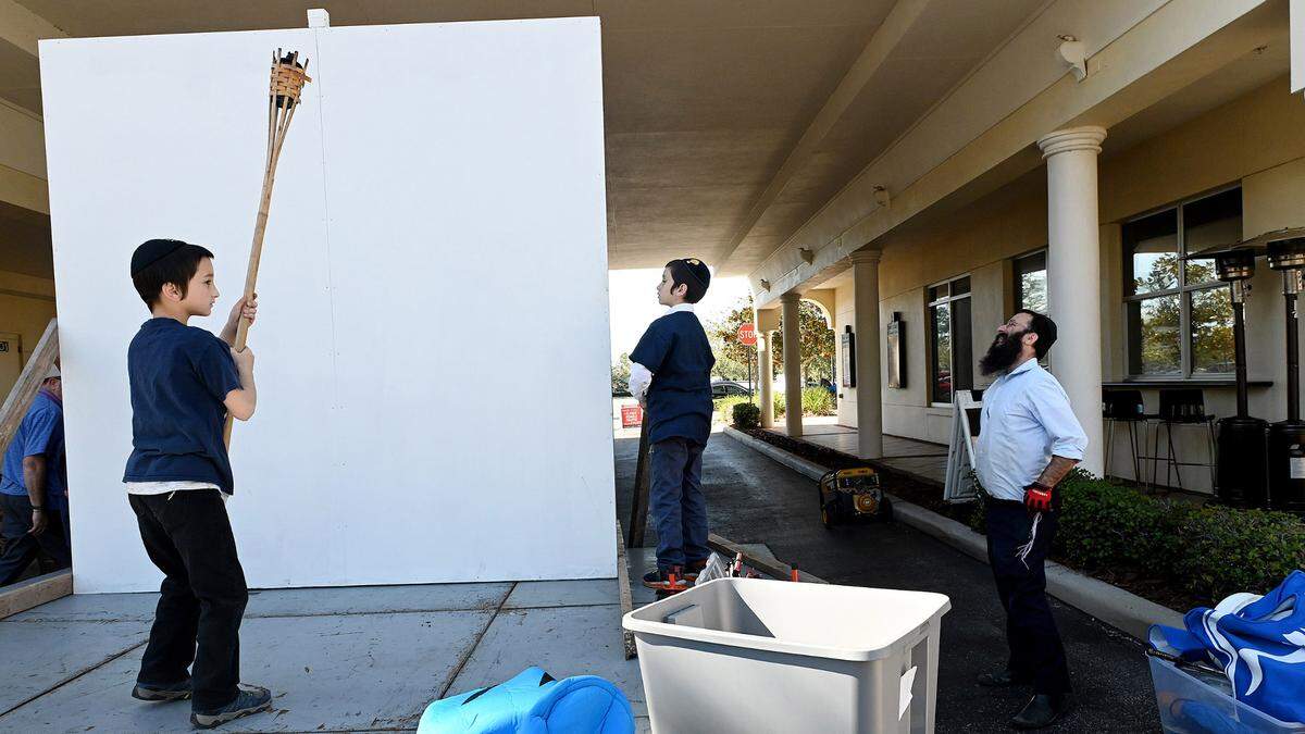 Rabbi Mendy Bukiet of the Chabad of Bradenton and Lakewood Ranch with two of his sons sets up what will be a large menorah for a celebration of the second night of Hanukkah on Lakewood Ranch Main Street.