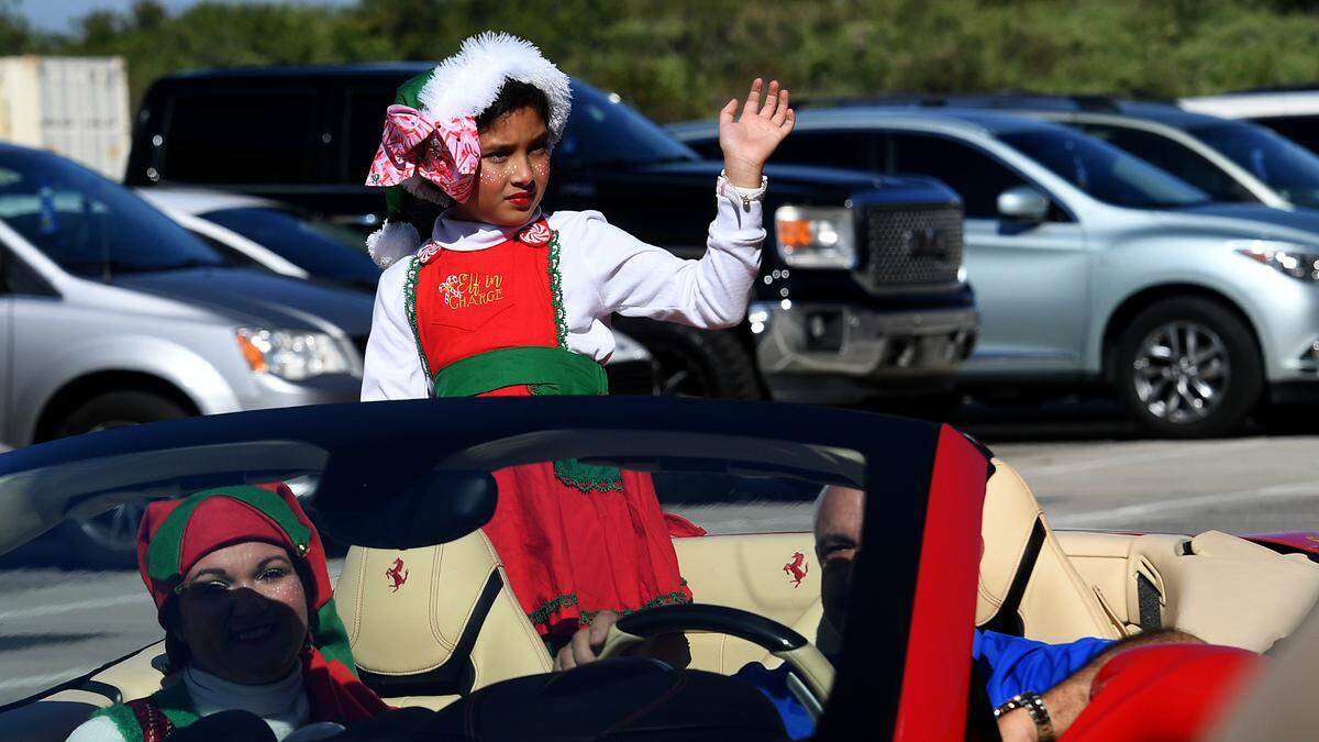 A child in festive holiday attire waves to the crowds at the 37th annual Flight to the North Pole program for children with disabilities and terminal illness and their families. The event was founded by Sidney Ettedgui of the Manatee County Sheriff’s Office and Eastern Airline Flight attendants with the help of the Sarasota/Bradenton Airport Fire Dept. and Feld Entertainment.