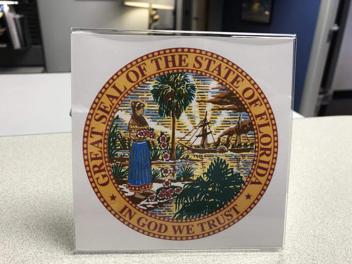 The Great Seal of the State of Florida, framed in acrylic and displayed in a Seminole County Public Schools building. Florida school districts used the seal to meet a 2018 law requiring the state motto, “In God We Trust,” to appear in public campuses.