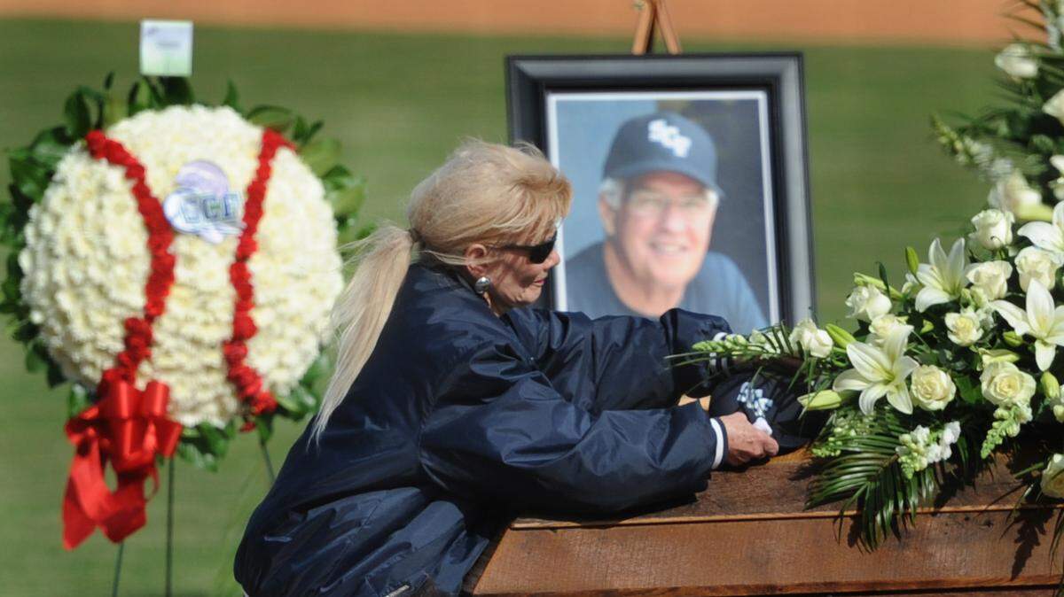 Genevieve Hill, the wife of former State College of Florida baseball coach Tim Hill, places an SCF baseball cap on her husband's casket. GRANT JEFFERIES/Bradenton Herald