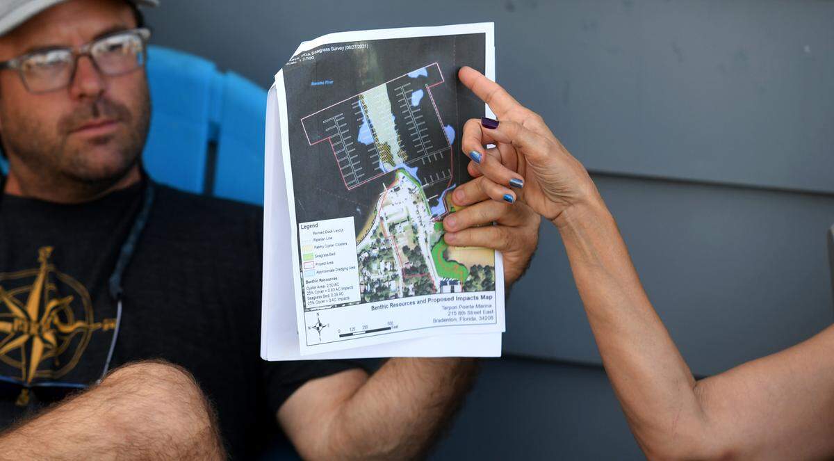 Bryan Zoller, background, holds a rendering of a proposed expansion of Tarpon Pointe Marina. Residents of Riverview Blvd. East near Tarpon Pointe are worried about the effects of a proposed 200-plus boat slip marina expansion on the environment and their views.