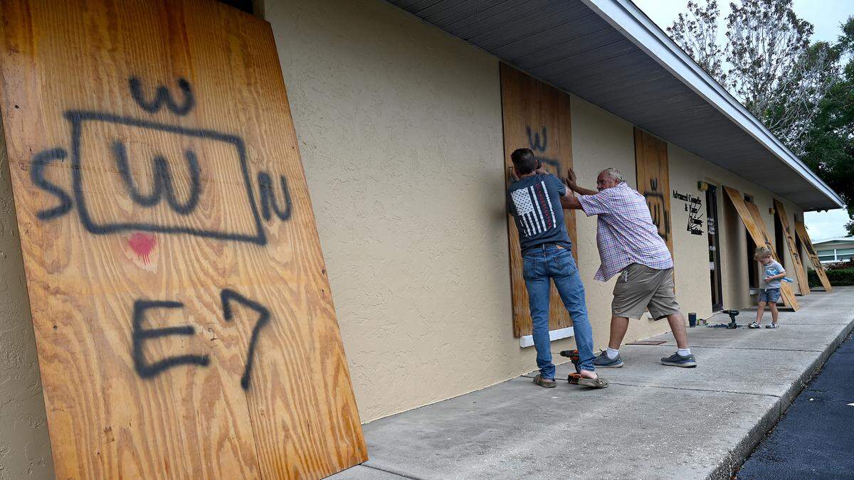 Gerald Grace and Paul Connors board up a friend’s business while Branson Ellard, 4, watches as Hurricane Milton approaches Manatee County on Oct. 7, 2024.
