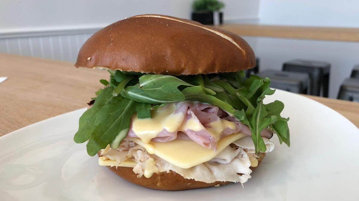 6/1/2021--The Cheesecake Cutie & Cafe opened at 3324 E. Bay Drive, Holmes Beach, in November. In addition to its cheesecakes, the cafe is now serving breakfast and lunch. Shown above is the Cordon “Ramsey” Blu, made with rotisserie chicken, ham, Swiss cheese, arugula, and house Dijon mustard, served on a pretzel roll.