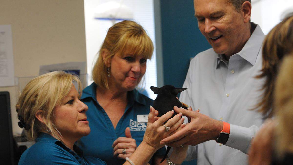 Valerie Bliss, development director, and Terri Romano, veterinary practice manager, talk with U.S. Rep. Vern Buchanan as he holds Troubbles, a 6-week-old Chihuahua, during a tour Monday of the Pet Health Center at the Humane Society of Manatee County. 
 GRANT JEFFERIES/Bradenton Herald