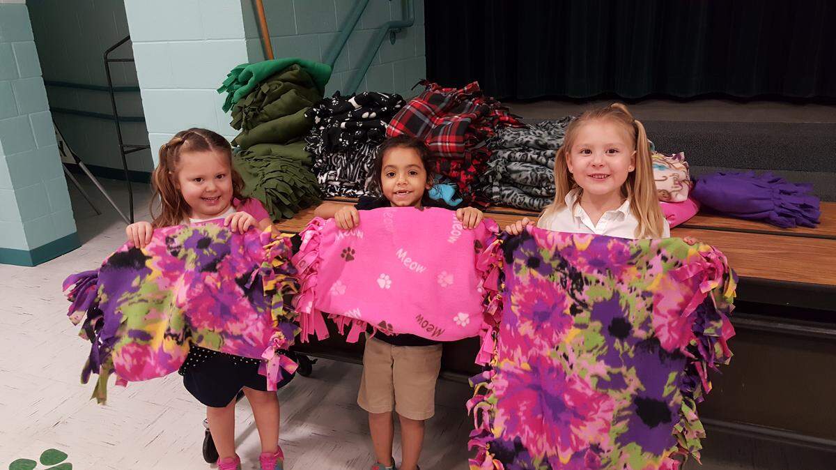 Students from Oneco Elementary School hold up blankets they've made that will help vetearns stay warm during the winter months. PROVIDED PHOTO