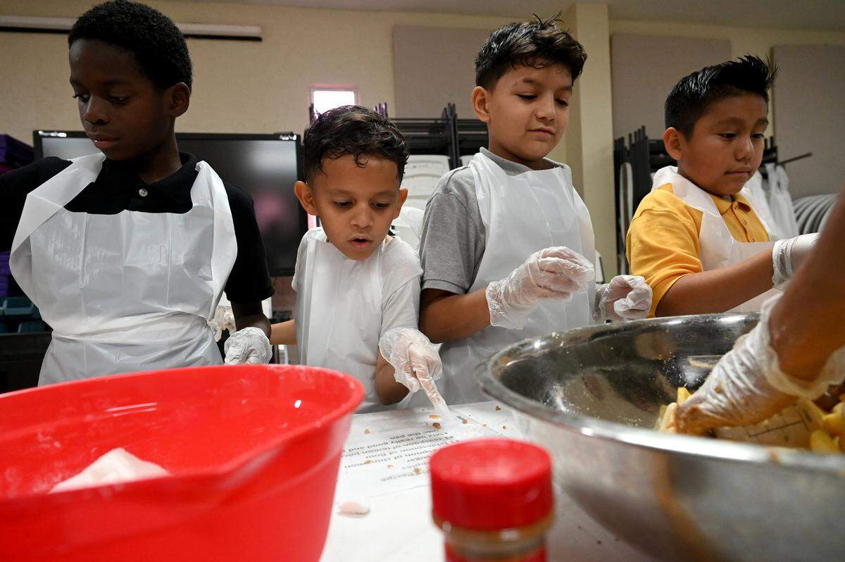 Students check a recipe while they make apple pies for their families’ Thanksgiving celebrations at Visible Men Academy on Friday, Nov. 17, 2023.