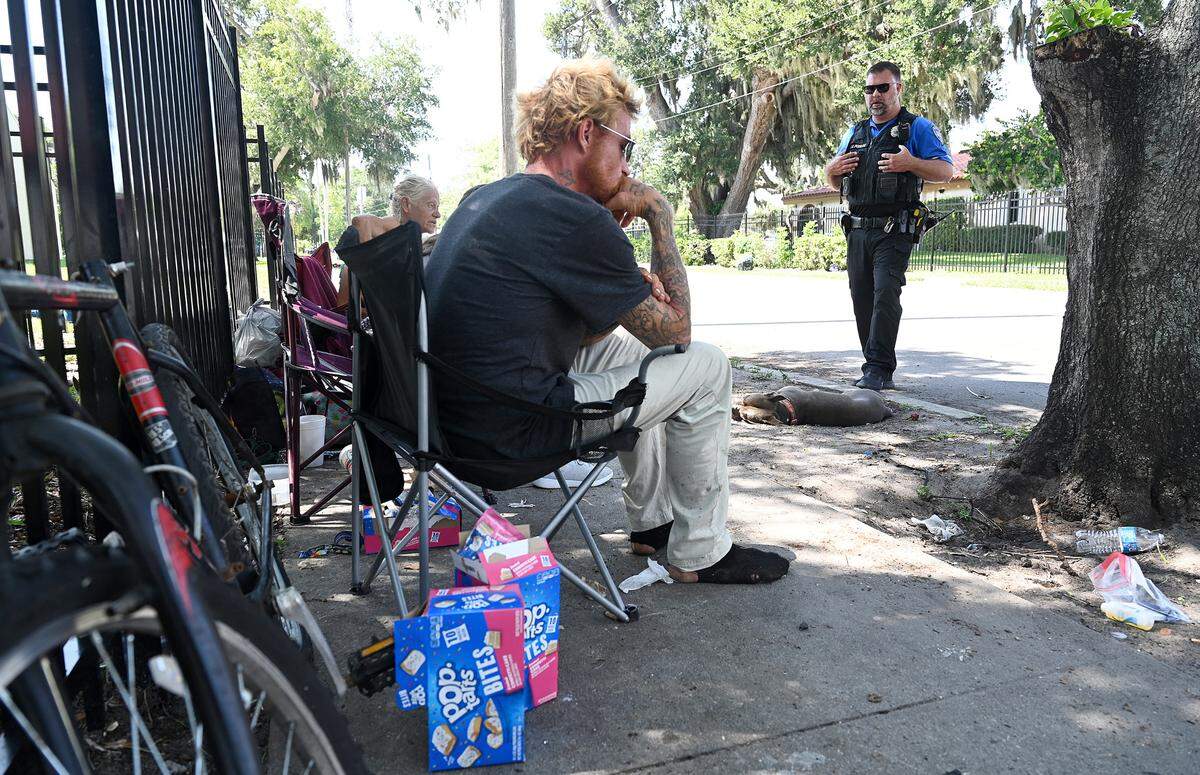 Bradenton police officer Jordan Poulos talks to people without housing on the street behind the Salvation Army on 14th Street West in this Bradenton Herald file photo.