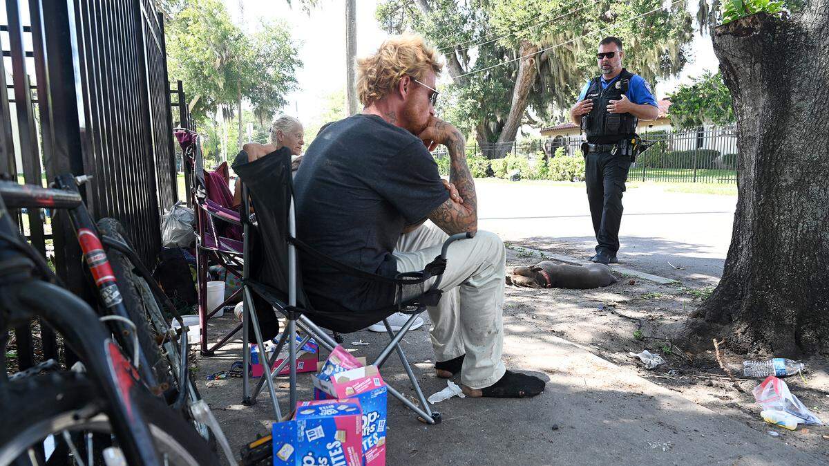 Bradenton police officer Jordan Poulos talks to people without housing on the street behind the Salvation Army; asking how they are and if he could help them in any way. One woman said she needed assistance filing a police report and obtaining identification, and another person expressed an interest in getting help with substance abuse. Poulos took notes and said he would work on their needs.