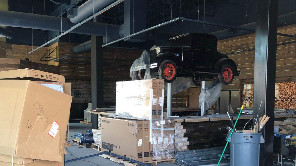 4/5/2021--Ford’s Garage is advertising outside its soon-to-open restaurant in the University Town Center location that it is hiring. Inside, antique Ford motorcars have been suspended from the ceiling.