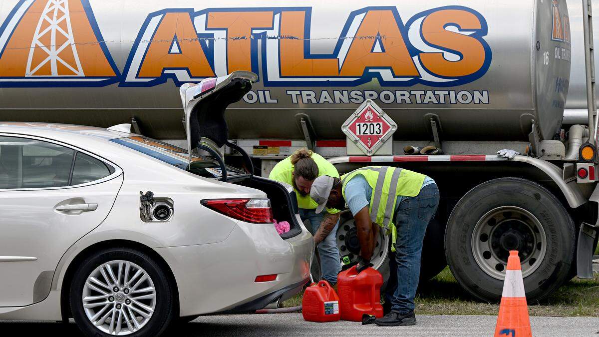 Fuel workers fill up a motorist’s gas cans at Tom Bennett Park in Bradenton, where residents can get 10 free gallons of gas, on Saturday, Oct. 12, 2024.