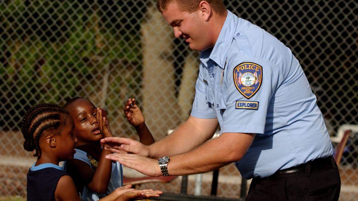 Bradenton Police Department Explorer Jason Varrato, right, gives Devontae Davis, 5, left, and Bryan Coleman, 6, high and low fives after each boy received a "Junior Officer" sticker from the Explorers during the National Night Out block party at the East Bradenton Boys and Girls Club Tuesday night. Photo Alex Diaz 08.05.2003
