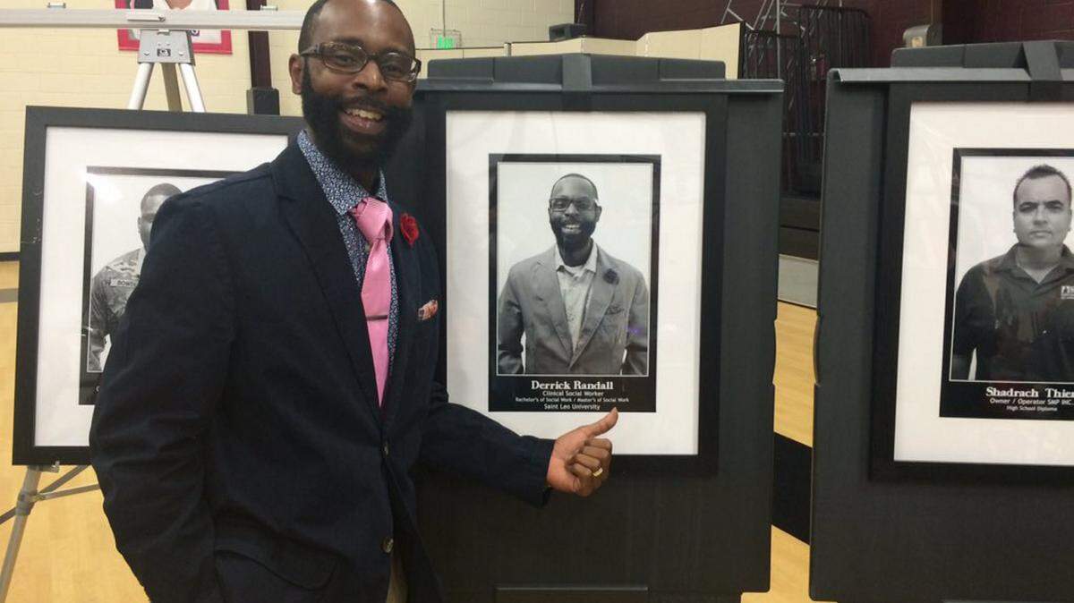 Derrick Randall, a clinical social worker, poses with a photograph taken of him Friday evening after an art exhibit featuring 25 community members who have each obtained success.AMARIS CASTILLO/Bradenton Herald