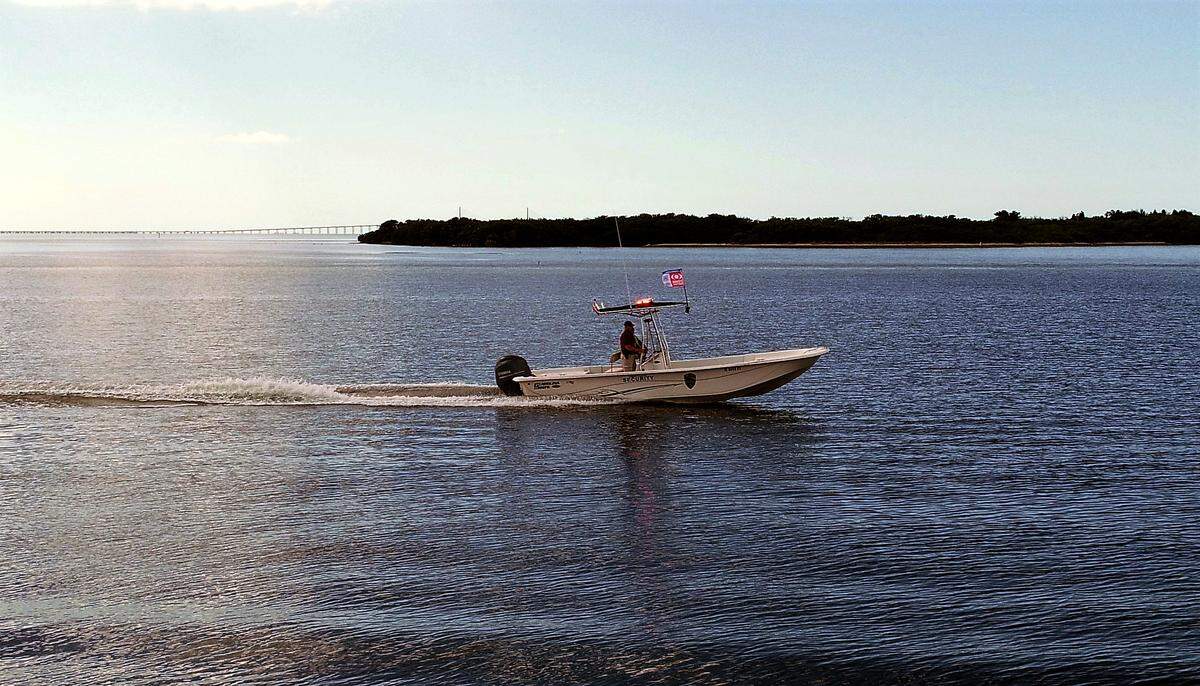 A Port Manatee security patrol boat flies a Zone Watch flag while passing through waters around Manbirtee Key in lower Tampa Bay.