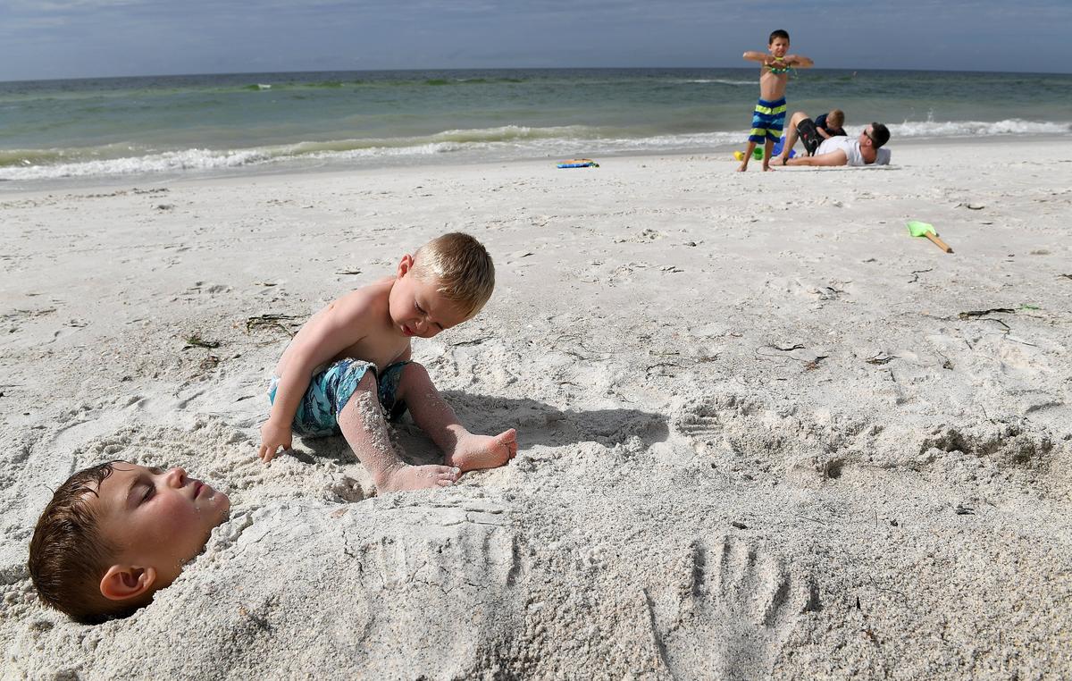 Visitors, including Bennett and Hudson Chappell, 3 and 5, enjoy the sun and sand at the Manatee County Public Beach Tuesday.