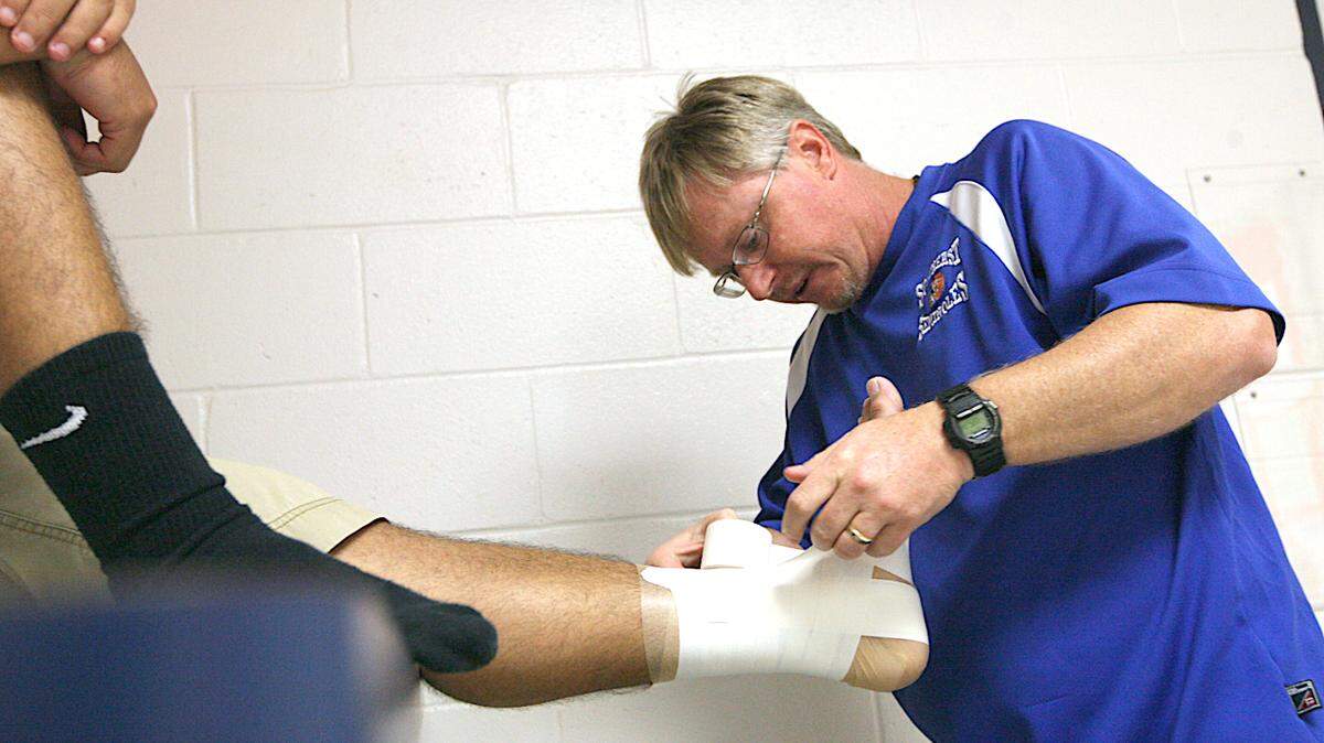 John Karl tapes an athlete at Southeast High School on April 16, 2011, shortly after being named Florida High School Athletic Trainer of the Year. HERALD FILE PHOTO