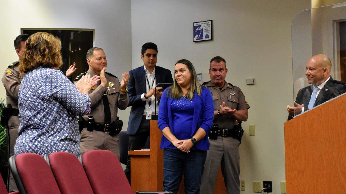 Florida Highway Patrol Trooper Toni Schuck (center) looks on during a standing ovation from the audience on Tuesday, March 22, 2022, which the Manatee Board of County Commissioners declared “Toni Schuck Day” after she used her FHP vehicle to prevent a deadly crash during the annual Skyway 10K race on March 6, 2022.
