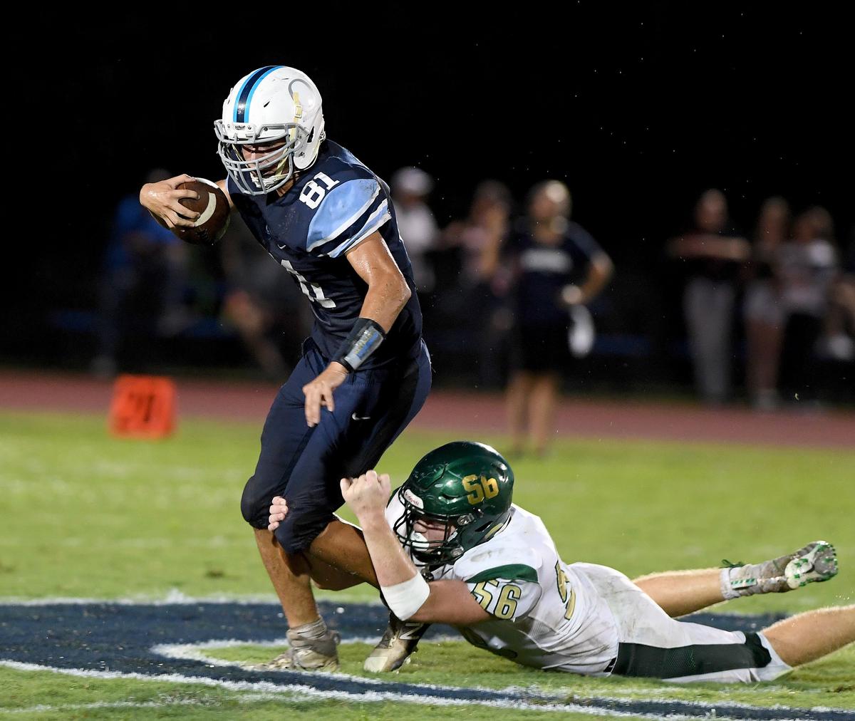Out of Door Academy’s Colin Castro runs with St. Stephen’s Tyler Burnham holding fast during Friday night’s game at Out of Door Academy.
