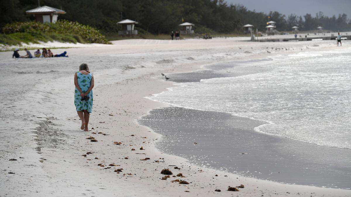 A woman walks along the shoreline at Cortez Beach in Bradenton Beach ahead of Tropical Storm Nicole on November 9, 2022.