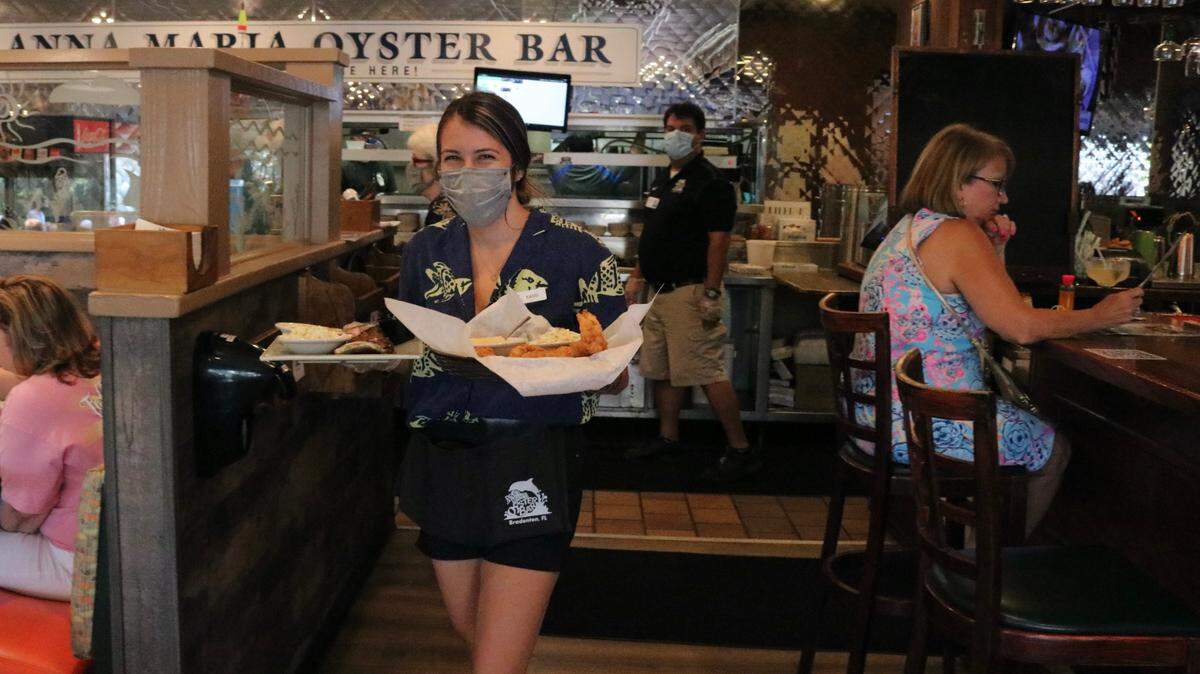 4/27/2021--Kassi Sands delivers meals at the Anna Maria Oyster Bar Restaurant, 1525 51st Ave. E., Ellenton. Restaurant owner John Horne says his staff is working hard, but he has had difficulty recruiting more associates.