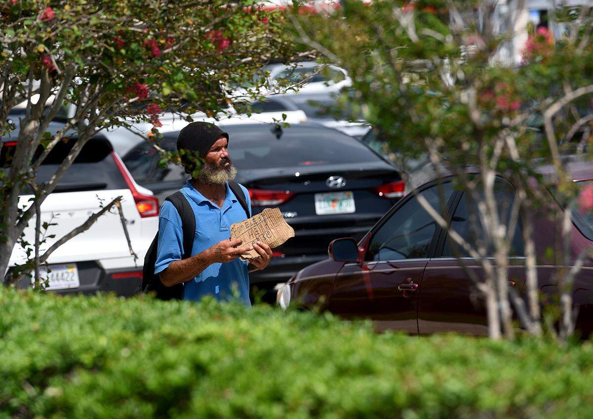 A panhandler works on the corner of Sixth Avenue and First Street West in Bradenton during a summer afternoon.