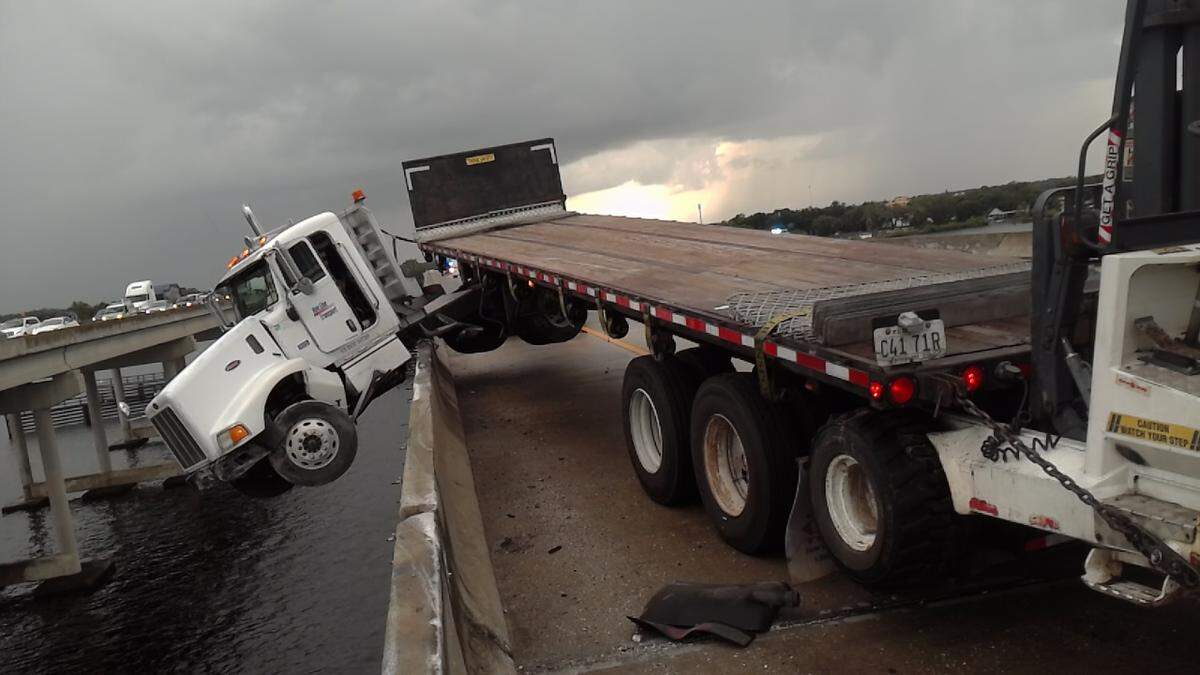 A semi-truck dangled over the edge of the Trooper JD Young Bridge just south of U.S. 301 in Manatee County for about two hours after a crash Friday morning. The crash temporarily shut down the northbound lanes of Interstate 75.
