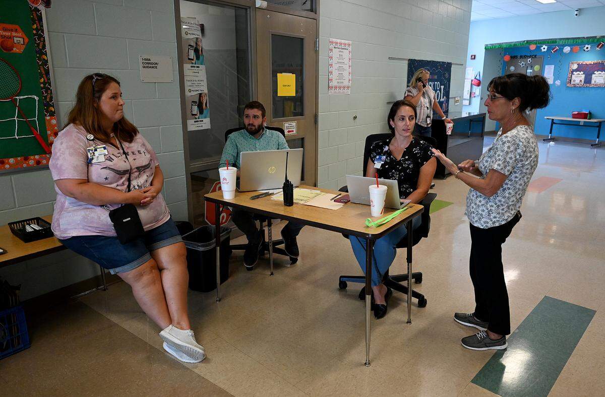 Seated at table Evan McCarthy and Shannon Fleming from the school district register residents checking into the Jesse P. Miller Elementary School shelter in preparation for Idalia’s expected strengthening and approach on August 28, 2023.
