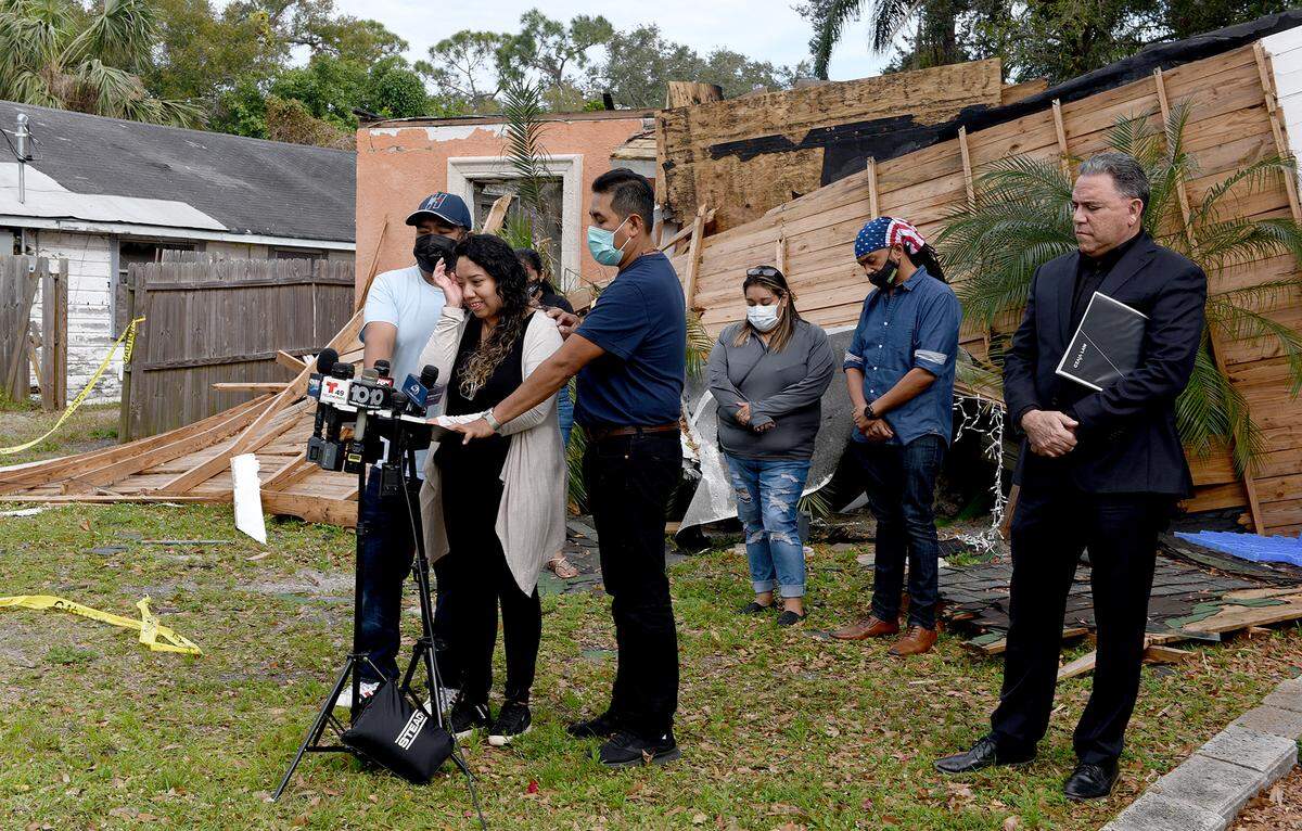 01/15/21--Karina Lopez, center at lectern, is surrounded by family and friends in front of her home which was destroyed in a gas explosion and fatally wounded her brother, Adrian Lopez, Jr.
