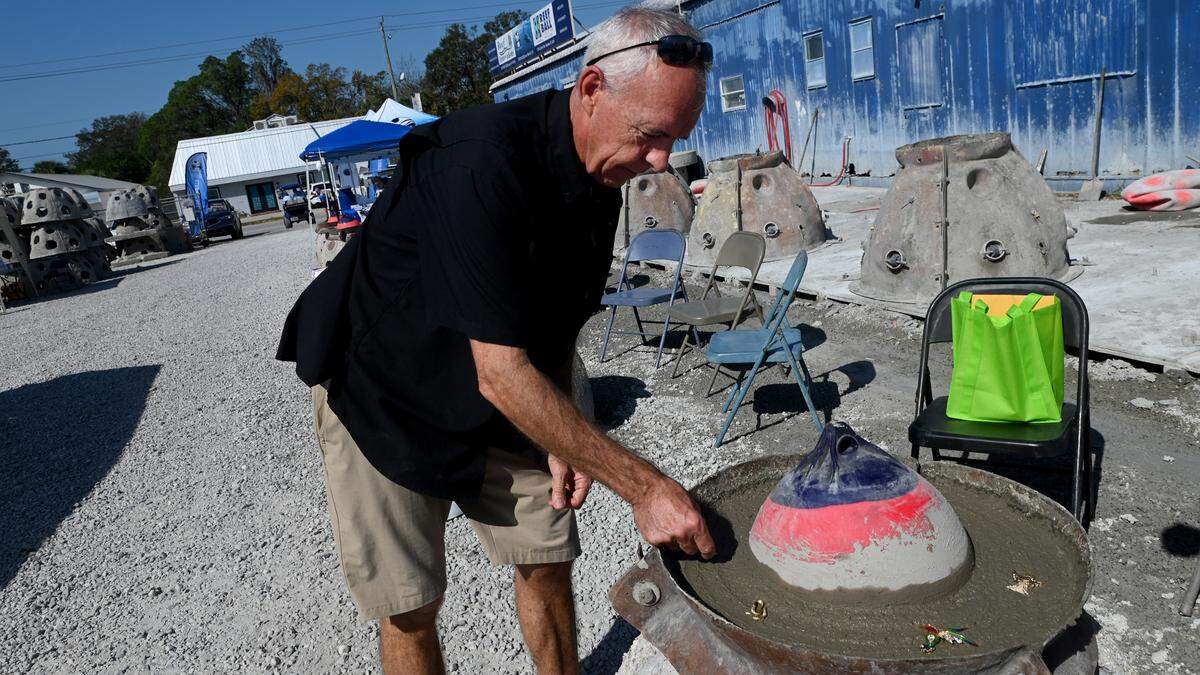 Tom Ries adds a colorful piece of his mother, Gisela’s, costume jewelry to an eternal reef with her cremated remains incorporated into the structure. “This will attract a lot of fish,” said Ries, who said his mother loved fishing.