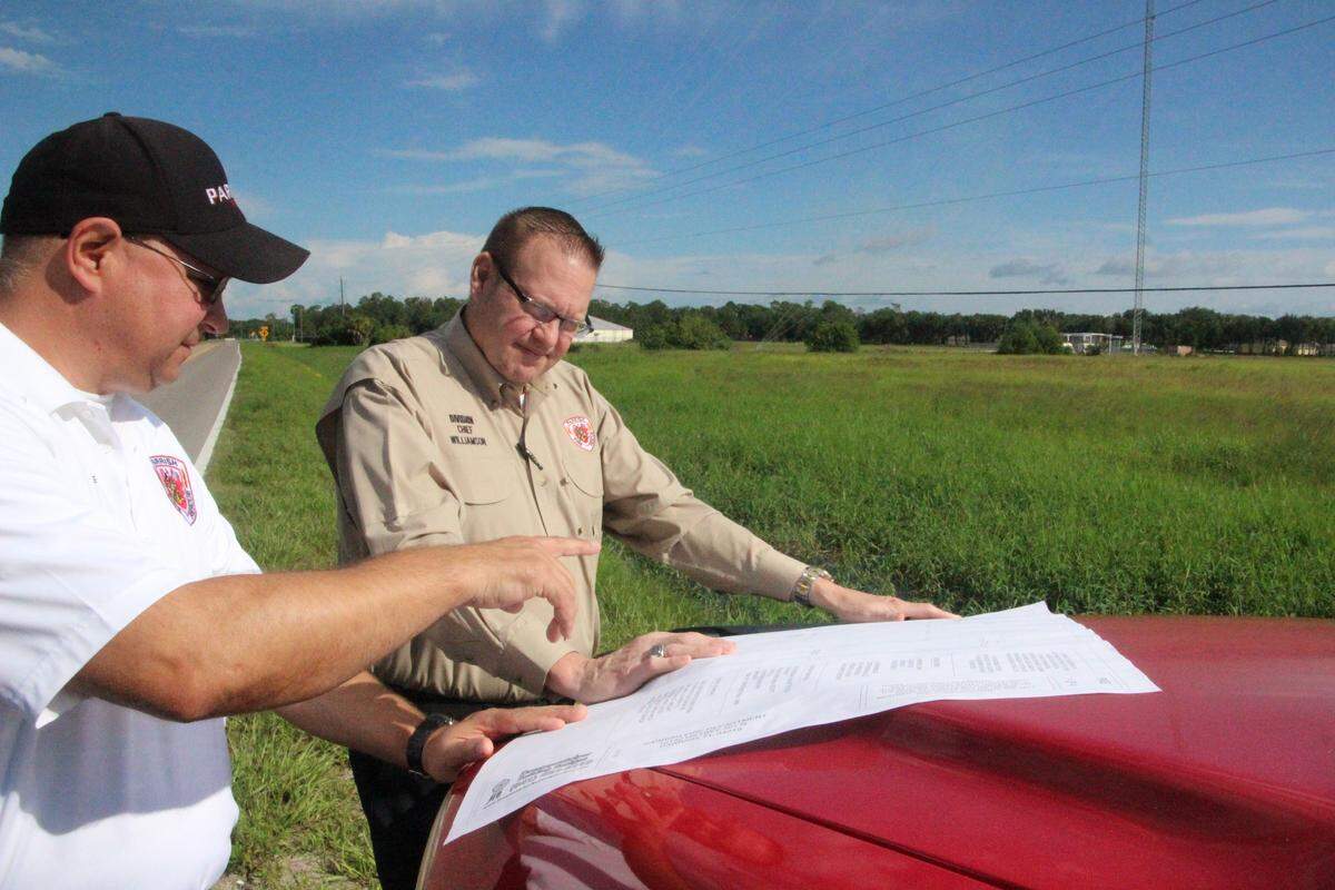 Parrish Fire Chief Stacey Bailey, left, and Division Chief Michael Williams, look at plans for the district's second fire station to be located off State Road 675 in Foxbrook, shown above.