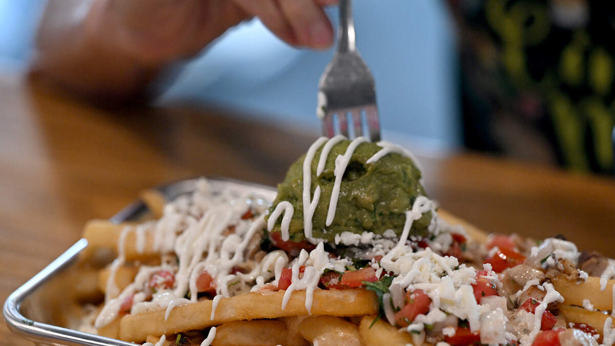 A customer digs into the Cali Fries at Los Chiludos on opening day, June 4, 2026, in the Braden River shopping plaza on State Road 64 East.