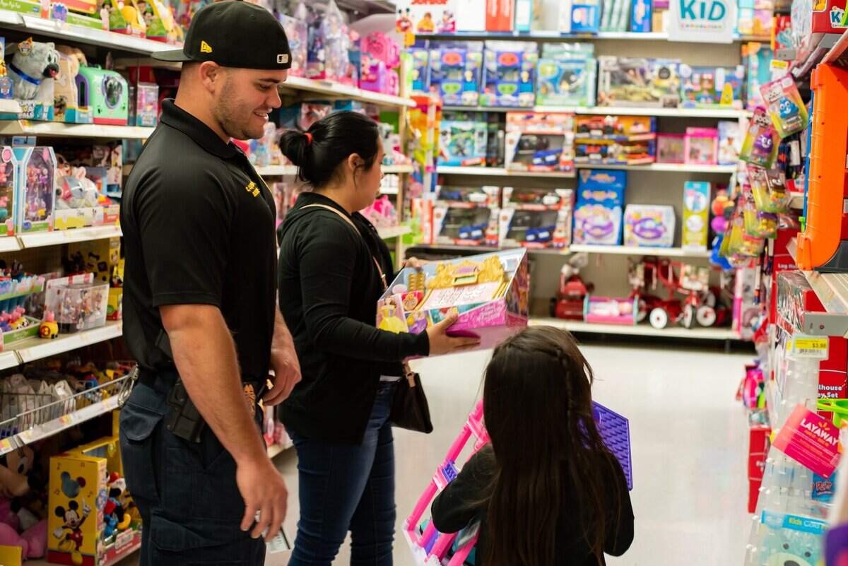 Bradenton Police Department detective Christopher Capderast helps a child select Christmas presents at Walmart during the Honoring the Badge event.