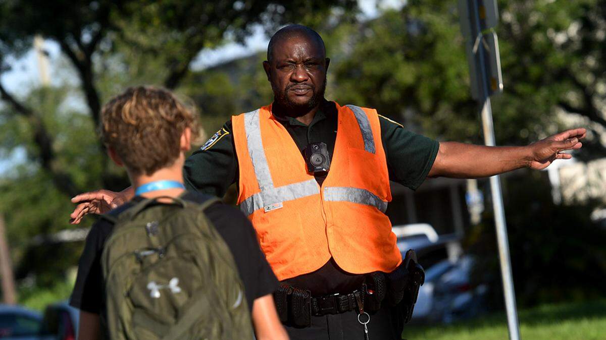 08/09/21—A crossing guard with the Manatee County Sheriff’s office stops traffic for students headed to King Middle School on the first day of classes in Manatee County.